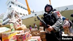 មន្រ្តីប៉ូលិសការពារជំនួយស្បៀងអាហារ ដែលនឹងត្រូវយកទៅចែកជូនជនរងគ្រោះ ដោយសារគ្រោះរញ្ជួយដី និងរលកយក្សស៊ូណាមិ នៅ​​ក្រុង Palu កោះស៊ូឡាវេស៊ី ប្រទេសឥណ្ឌូនេស៊ី។ 