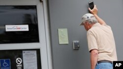 John Poe, a small business owner, speaks to an unseen state worker through an intercom speaker system at this state WIN job center in Canton,April 29, 2020. 