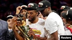 Kawhi Leonard admire avec Serge Ibaka, à droite, le trophée Larry O'Brien, après que Toronto a remporté le titre de champion NBA 2019, Oracle Arena, Oakland, Californie, le 13 juin 2019. (Kyle Terada-USA TODAY Sports) 