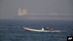 Sebuah kapal nelayan berlayar melintas sebuah tanker minyak di kejauhan di Fujaira, Uni Emirat Arab, 15 Juni 2019. 