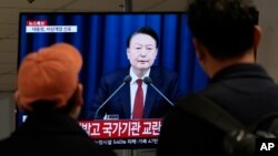 3일 한국 서울의 버스 터미널에서 시민들이 윤석열 한국 대통령의 비상계엄 선포 보도를 시청하고 있다.