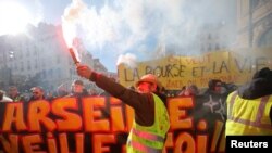 A protester wearing a yellow vest holds a flare as he takes part in a demonstration of the "yellow vests" movement in Marseille, France, January 26, 2019. 