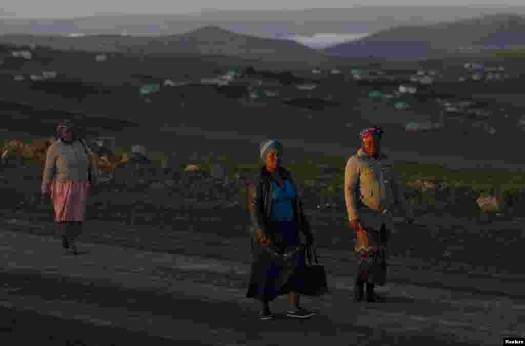 Beberapa perempuan berjalan ke tempat umum di dekat lokasi pemakaman untuk menyaksikan upacara pemakaman mantan presiden Afrika Selatan Nelson Mandela di Qunu, Afrika Selatan, 15 Desember 2013.