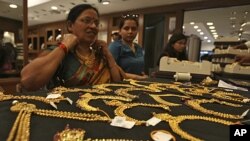 A customer tries on a gold necklace inside a jewelry showroom in the southern Indian city of Hyderabad, April 11, 2012.