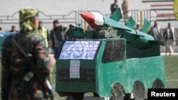 A Houthi militant stands in front of a cardboard model of a missile during a gathering to mark 1,000 days of the Saudi-led military intervention in the Yemeni conflict, in Sana'a, Yemen Dec. 21, 2017.