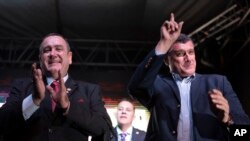 Alejandro Giammatei, presidential candidate of the Vamos party, left, and his running-mate Guillermo Castillo, stand before supporters after partial election results were announced in Guatemala City, Sunday, Aug. 11, 2019. 