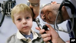 FILE - A child has his ear examined by a doctor at Children's Hospital of Pittsburgh, in Pittsburgh, Nov. 20, 2006.