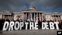 Backdropped by Britain's National Gallery in central London, protesters hold placards during a rally to show solidarity with Greece, Sunday, Feb. 15, 2015. 