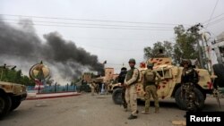 FILE - Afghan security forces keep watch at the site of an explosion in Jalalabad city, Afghanistan, May 13, 2018. On Friday three explosions rocked a cricket stadium.