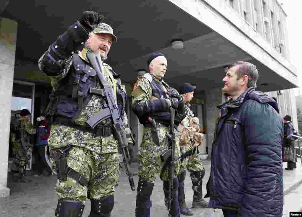 A local resident talks to pro-Russian armed men standing guard outside the mayor&#39;s office in Slovyansk, Ukraine, April 14, 2014.