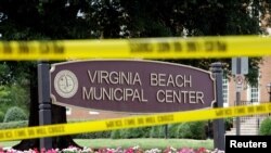 Police tape frames a sign at one of the entrances to the municipal government complex where a shooting incident occurred in Virginia Beach, Virginia, June 1, 2019.