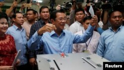 Cambodian Prime Minister Hun Sen prepares to cast his vote as his wife, Bun Rany, stands beside him at a polling station during a general election in Takhmao, Kandal province, Cambodia, July 29, 2018.
