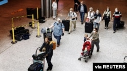 Passengers wearing face masks walk at the Helsinki-Vantaa airport in Vantaa, as Finnish Government has eased travel restrictions with several EU countries following the coronavirus disease (COVID-19) outbreak, in Finland, July 13 2020. 