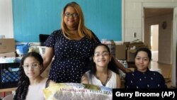  Aja Purnell-Mitchell stands next to her three children, Kyla, 13, left; Kyra, 15, and Cartier, 14, at a local food hub in Durham, N.C., on Friday, May 28, 2021, where they often help their mother. (AP Photo/Gerry Broome)