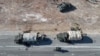 An aerial photo shows anti-government figthers riding a motorcycle past Syrian army military equipment and vehicles that were abandoned on the highway to Damascus, as they reach the town of Suran north of Syria's Hama city on Dec. 3, 2024.