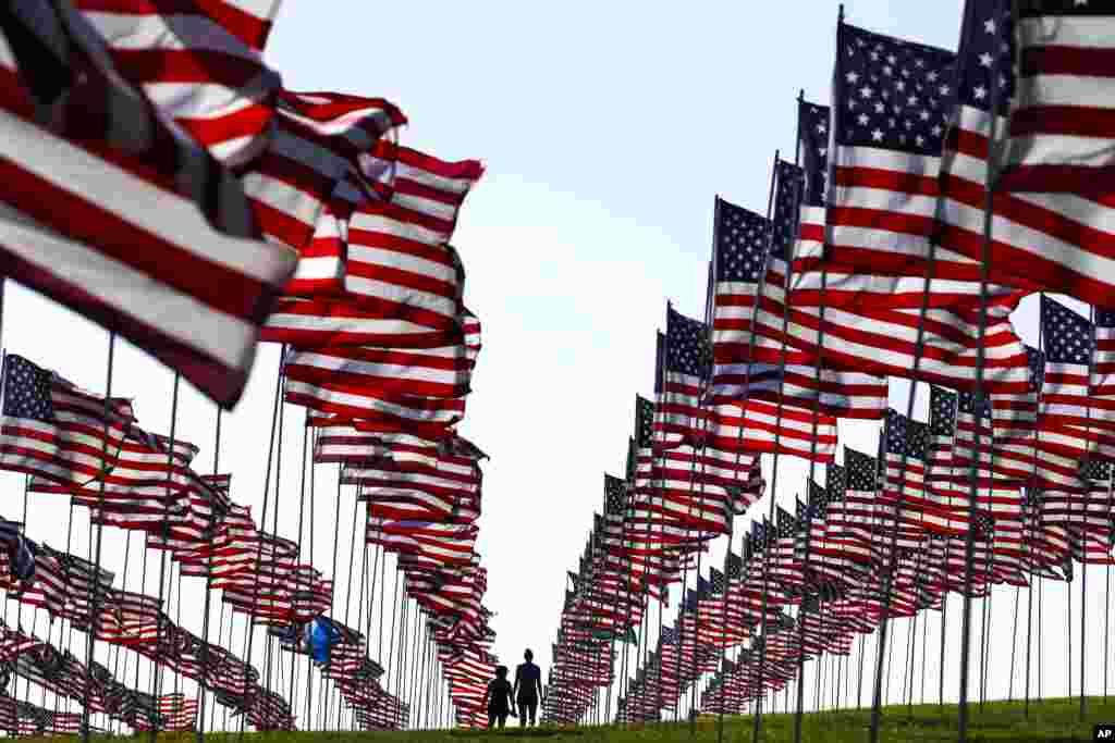 Bianca Burton, center left, and Erin Schultheis walk through Pepperdine University's annual display of flags honoring the victims of the 9/11 terrorist attacks, in Malibu, California, Sept. 10, 2018.