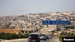 FILE - A journalists' convoy is seen at the entrance of Khan Sheikhoun, Idlib, Syria, Aug. 24, 2019.