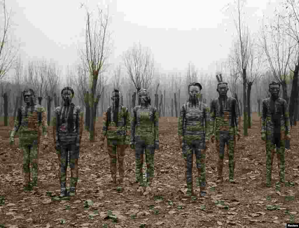 Models painted in camouflage colors to blend in with the background pose for Chinese artist Liu Bolin&#39;s artwork &quot;Dongji&quot;, or Winter Solstice, in Beijing.&nbsp;In this artwork, Liu wants to express his concerns about China and its people, including air pollution problem, he told Reuters.