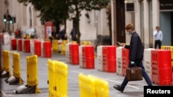 A man wearing a face mask crosses a road laid out with social distancing barriers in the City of London financial district amid the outbreak of the coronavirus disease, in London, Britain, Sept. 23, 2020. 