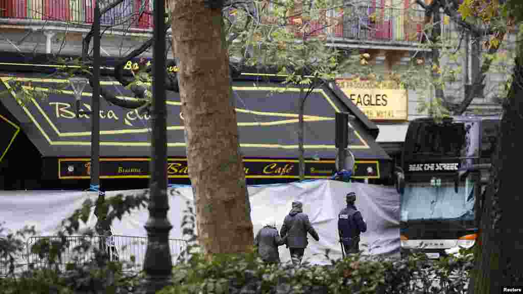 People walk past the screened-off facade of the Bataclan Cafe and its adjoining concert hall the day after a series of deadly attacks in Paris, Nov. 14, 2015. 