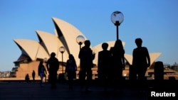 FILE - People walk in front of the Sydney Opera House, Australia, Nov. 2, 2016.
