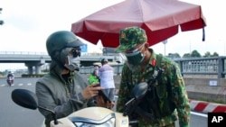 An army soldier checks identifications at a COVID-19 lockdown checkpoint in Ho Chi Minh City, Vietnam, Aug. 23, 2021.