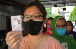 Indian women voters wearing face masks as a precaution against the coronavirus wait outside a polling station to cast their votes during the last phase of West Bengal state elections in Kolkata, April 29, 2021.