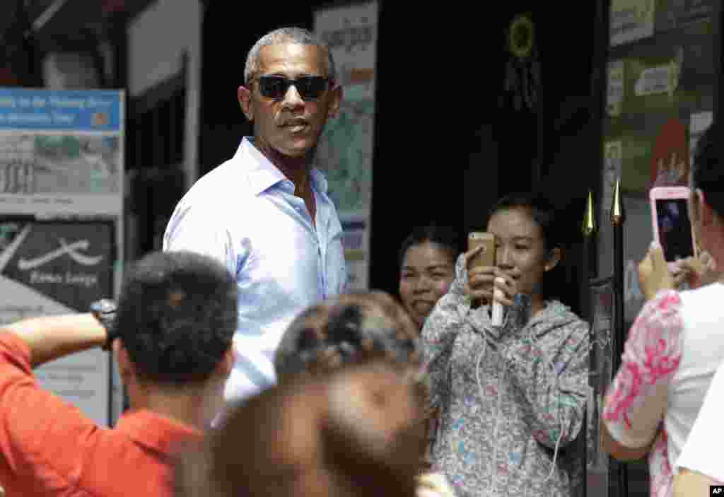 Local residents take photos of President Obama as he tours a shopping area near the Mekong River in the Luang Prabang, Sept. 7, 2016.