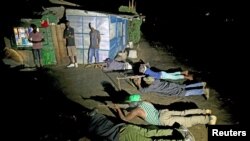 Armed vigilantes lay on the ground with their rifles as they patrol in the center of Bujumbura, Burundi, Nov. 20, 2015.