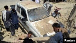Warga setempat berusaha membersihkan kendaraan dari reruntuhan akibat gempa di distrik Awaran – propinsi Baluchistan, Pakistan barat daya (25/9). 