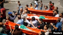 Mourners carry the bodies of three Palestinian teenage siblings from Abu Musalam family, who medics said were shelled by an Israeli tank inside their house, during their funeral in Beit Lahiya in the northern Gaza Strip on July 18, 2014.