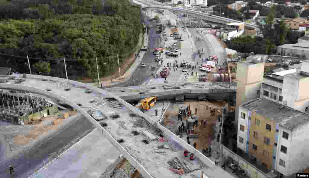 Rescue workers try to reach vehicles trapped underneath a bridge that collapsed while under construction in Belo Horizonte, July 3, 2014.