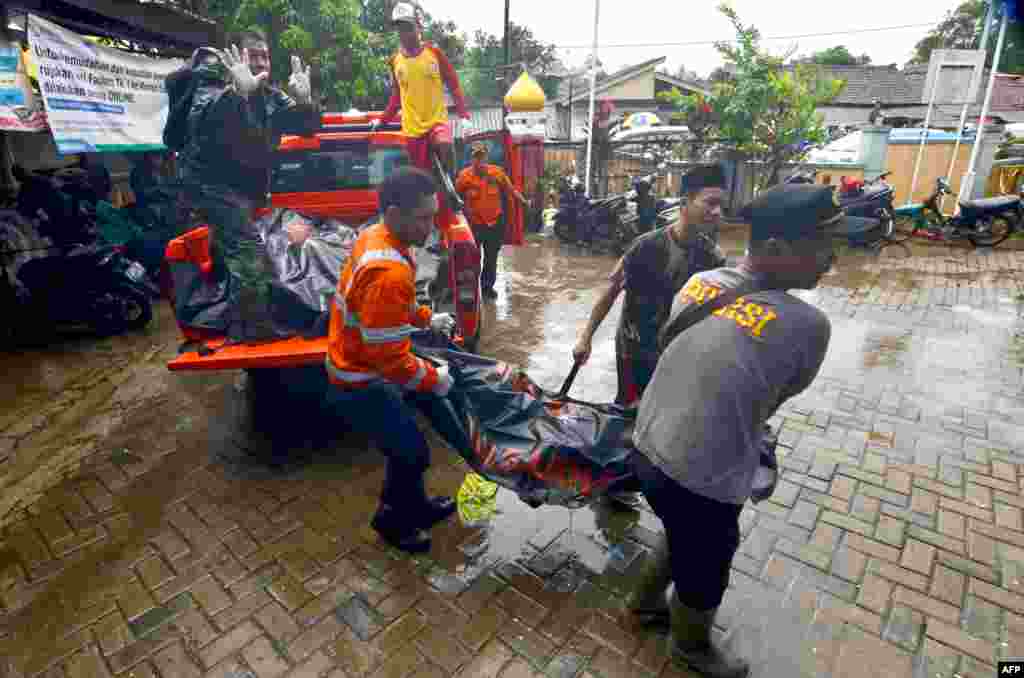 Rescuers carry body bags of victims to a makeshift mortuary in Carita, Dec. 23, 2018, after the area was hit by a tsunami Saturday following an eruption of the Anak Krakatoa volcano.