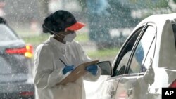 A health care worker takes down a patients information at a United Memorial Medical Center COVID-19 testing site, June 24, 2020, in Houston, Texas.
