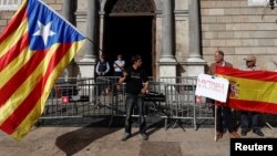 A man holding a Catalan separatist flag (L) looks at men holding a Spanish flag outside the Generalitat Palace, the Catalan regional government headquarters in Barcelona, Spain, Oct. 30, 2017. (REUTERS/Juan Medina)