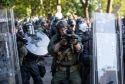 An Arlington County Police officer aims as demonstrators are moved back after gathering to protest the death of George Floyd, June 1, 2020, near the White House in Washington.