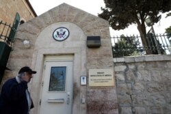 FILE - A man walks past a wall with plaques bearing the words "Embassy United States of America" at the premises of the former U.S. Consulate in Jerusalem, March 12, 2019.