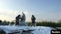 Firefighters spray foam on a wing of the Ural Airlines Airbus 321 passenger plane following an emergency landing in a field near Zhukovsky International Airport in Moscow Region, Russia, Aug. 15, 2019.
