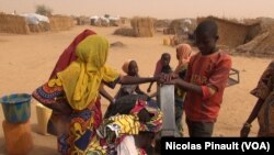 Des enfants autour d'une pompe à eau dans le camp de réfugiés d'Assaga, Diffa, Niger, le 17 avril 2017 (VOA/Nicolas Pinault)