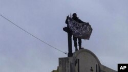 FILE - In this image posted on Twitter by Syria's al-Qaida-linked Nusra Front March 28, 2015, a Nusra Front fighter holds up his group's flag in Idlib province, northern Syria.