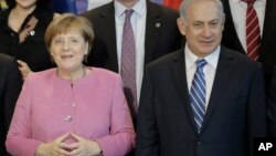 German Chancellor Angela Merkel, left, and the Prime Minister of Israel Benjamin Netanyahu, right, pose with government members for a group photo during a one day German-Israeli governmental meeting at the chancellery in Berlin, Germany, Feb. 16, 2016.
