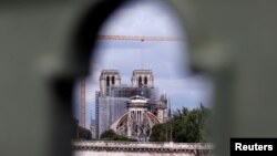 Para pekerja mulai menyingkirkan besi perancah di Gereja Katedral Notre Dame yang terbakar tahun lalu dan memulai pekerjaan restorasi, di Paris, 8 Juni 2020. 