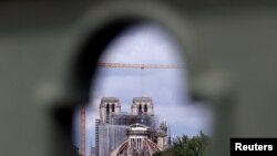 A view shows Notre Dame Cathedral, as workers prepare to remove damaged scaffolding elements from the remains of the burnt roof, in Paris, June 8, 2020. 
