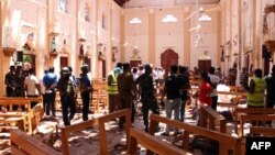 Sri Lankan security personnel walk through debris following an explosion in St Sebastian's Church in Negombo, north of the capital Colombo, on April 21, 2019.