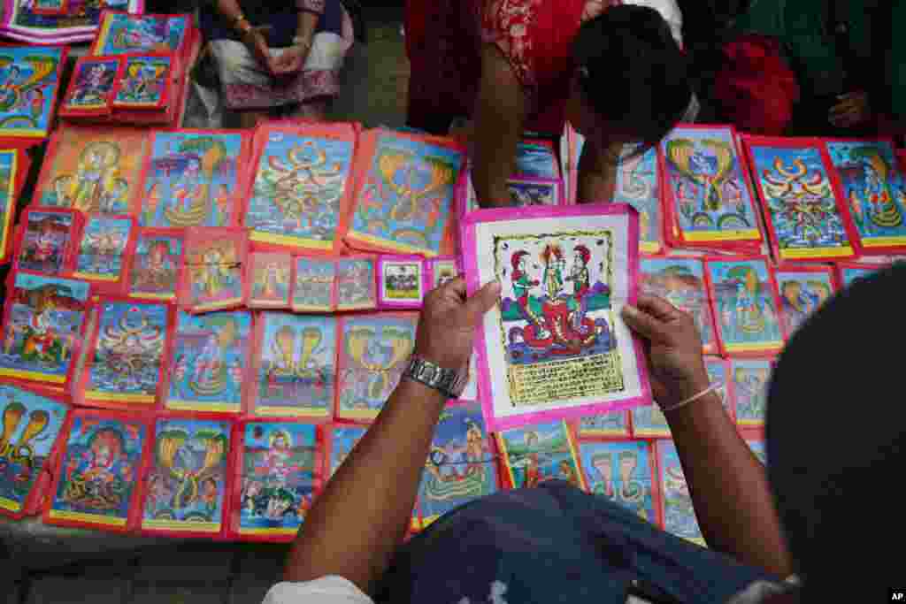 A Nepalese man checks a traditional painting displayed for sale at a market during Naag Panchami festival in Bhaktapur, Nepal, Aug. 4, 2019. 