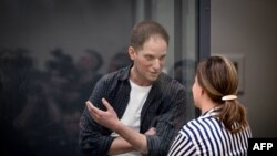 Wartawan AS Evan Gershkovich, yang ditangkap dengan tuduhan spionase, berbicara dengan pengacaranya usai sidang di Moskow, Rusia, 23 April 2024. (Foto: Natalia Kolesnikova/AFP)