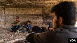 A group of Afghan men and boys waits bellow a small bridge to be picked up by the smuggler to continue their journey to Istanbul or other cities in Turkey, on Aug. 31, 2021. (VOA/Yan Boechat)