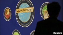 A man is silhouetted against the logo of the World Bank at the main venue for the International Monetary Fund (IMF) and World Bank annual meeting in Tokyo, October 10, 2012. 