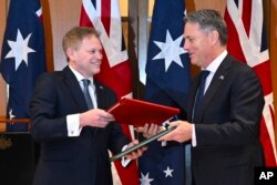 Menteri Pertahanan Inggris Grant Shapps, kiri, dan Menteri Pertahanan Australia Richard Marles bertukar perjanjian kerja sama pertahanan dan keamanan baru di Gedung Parlemen di Gedung Parlemen di Canberra, Kamis, 21 Maret 2024. (Lukas Coch/AAP Image via AP)