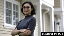 In this Monday, June 15, 2020, photo Xujiao Wang, 32, of East Providence, R.I., stands for a photograph outside her home. Wang works for a Massachusetts company and is on the Optional Practical Training program for student visa holders. (AP Photo/Steven Senne)